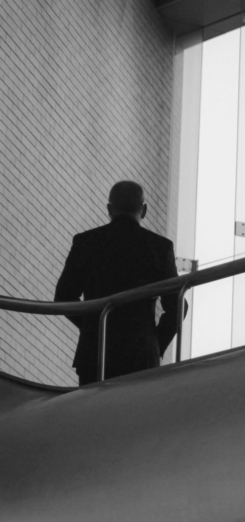 Man in suit leaning against a stairway rail looking at his phone